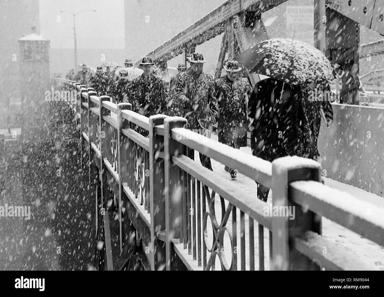 Pedestrians cross the State Street bridge over the Chicago River during a snowstorm,ca 1960. Stock Photo