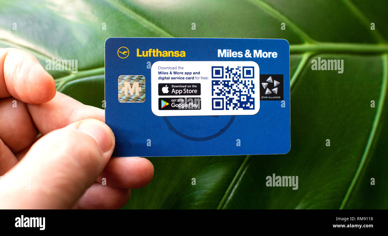 Frankfurt, Germany - Dec 18, 2018: Man holding against green leaf background a new Lufthansa Miles and More traveler loyalty programme card - contains protective advertising sticker Stock Photo