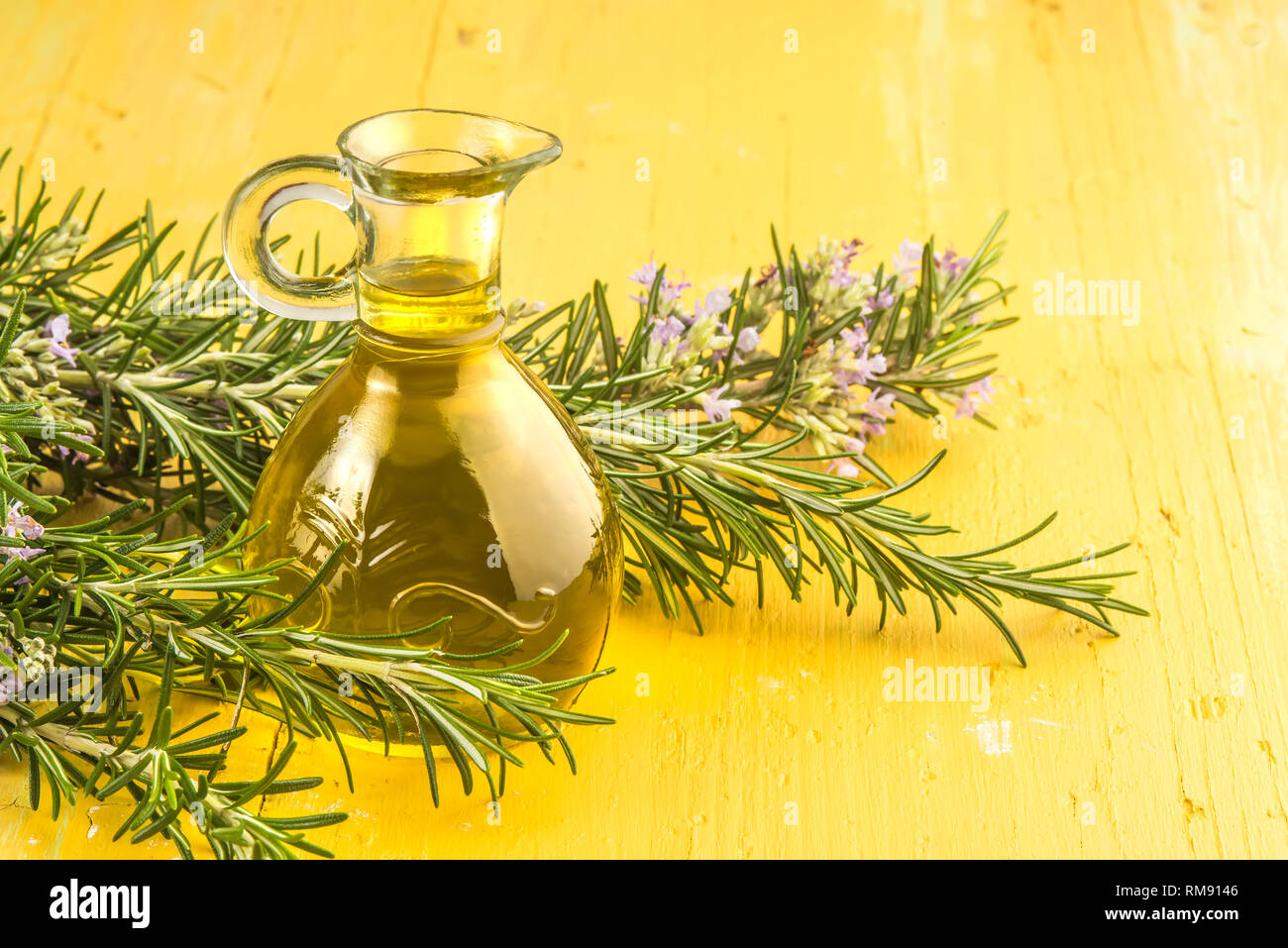 Extra virgin olive oil flavored with rosemary oil glass on a rustic