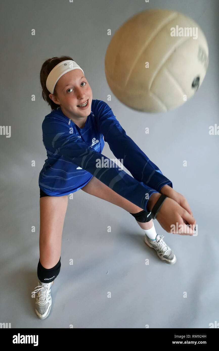 A girl bumps a volleyball while looking at the camera. Stock Photo
