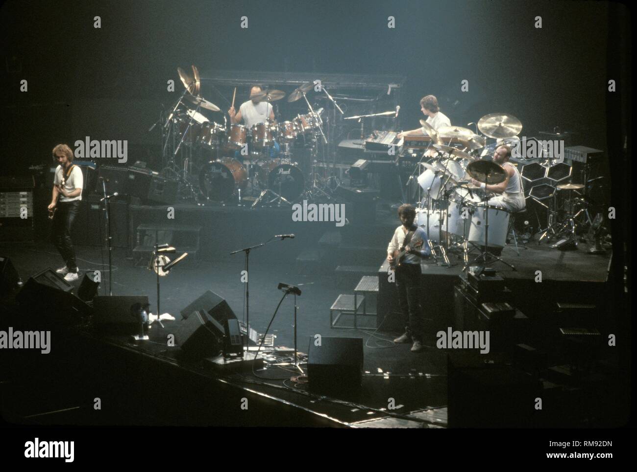 Genesis is shown performing on stage during a "live" concert