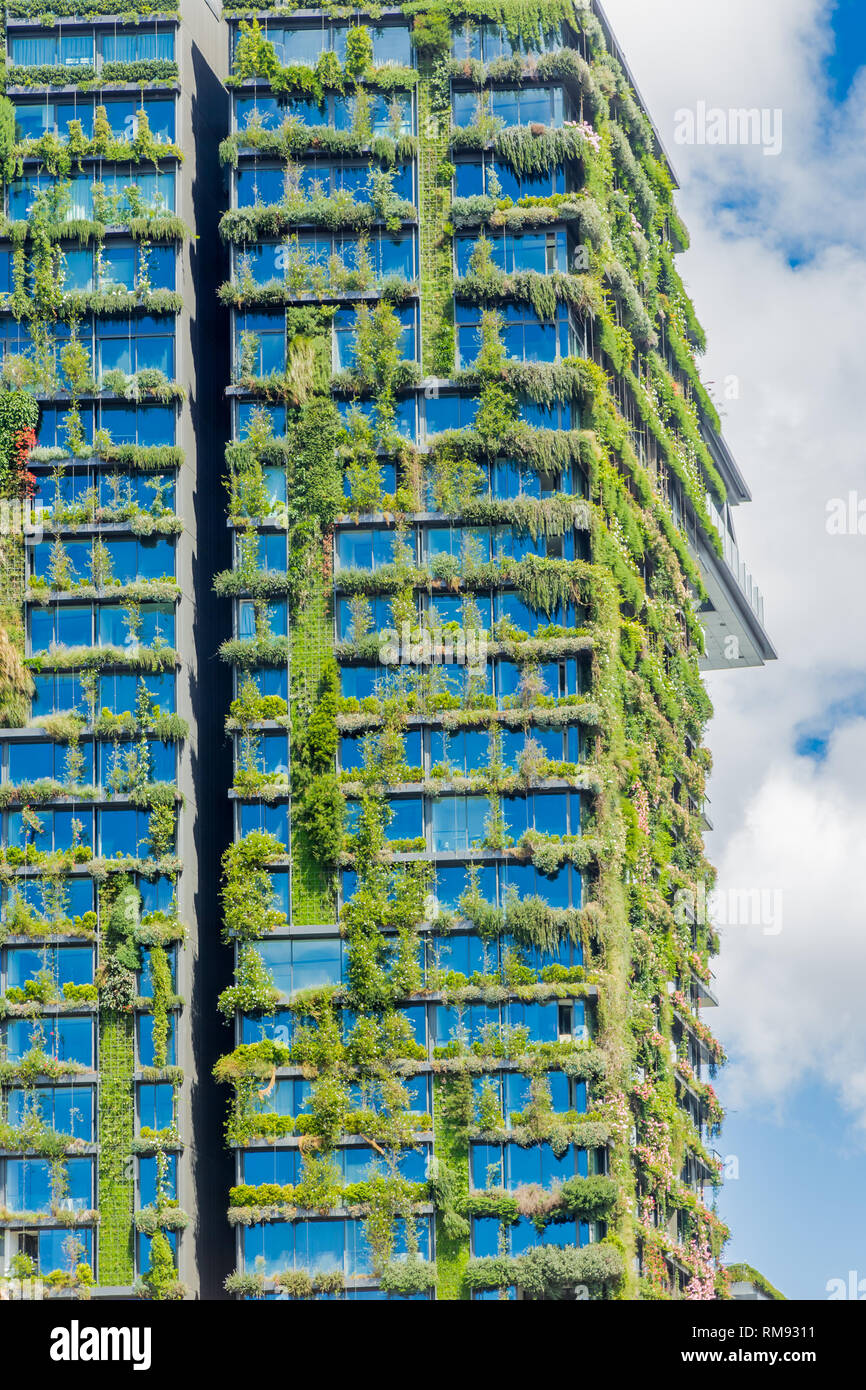 Green skyscraper building with plants growing on the facade. Stock Photo