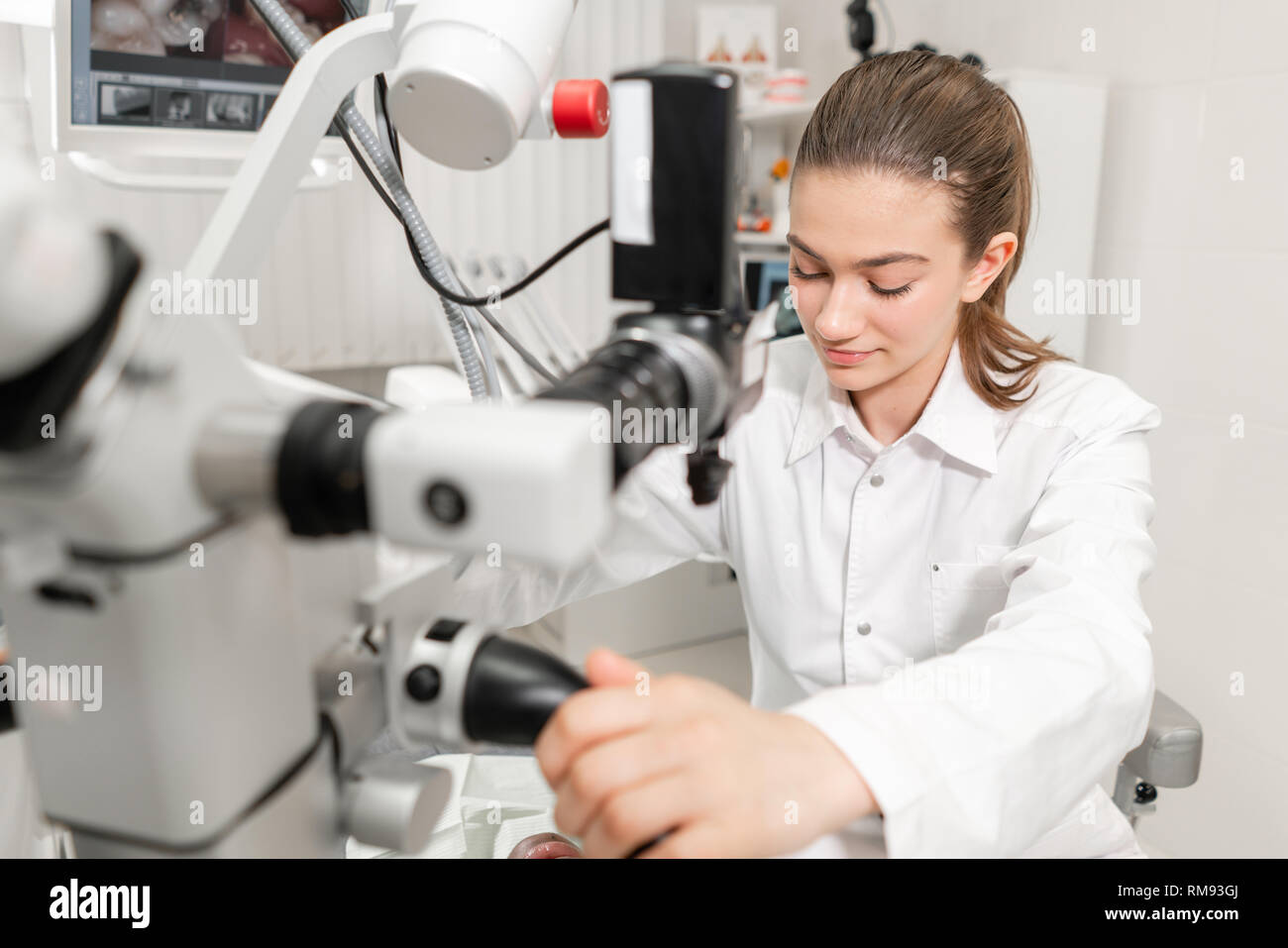 Female dentist advanced user, dental tools. Setup microscope for examining his patients teeth. in dental clinic office. Medicine, dentistry and health Stock Photo