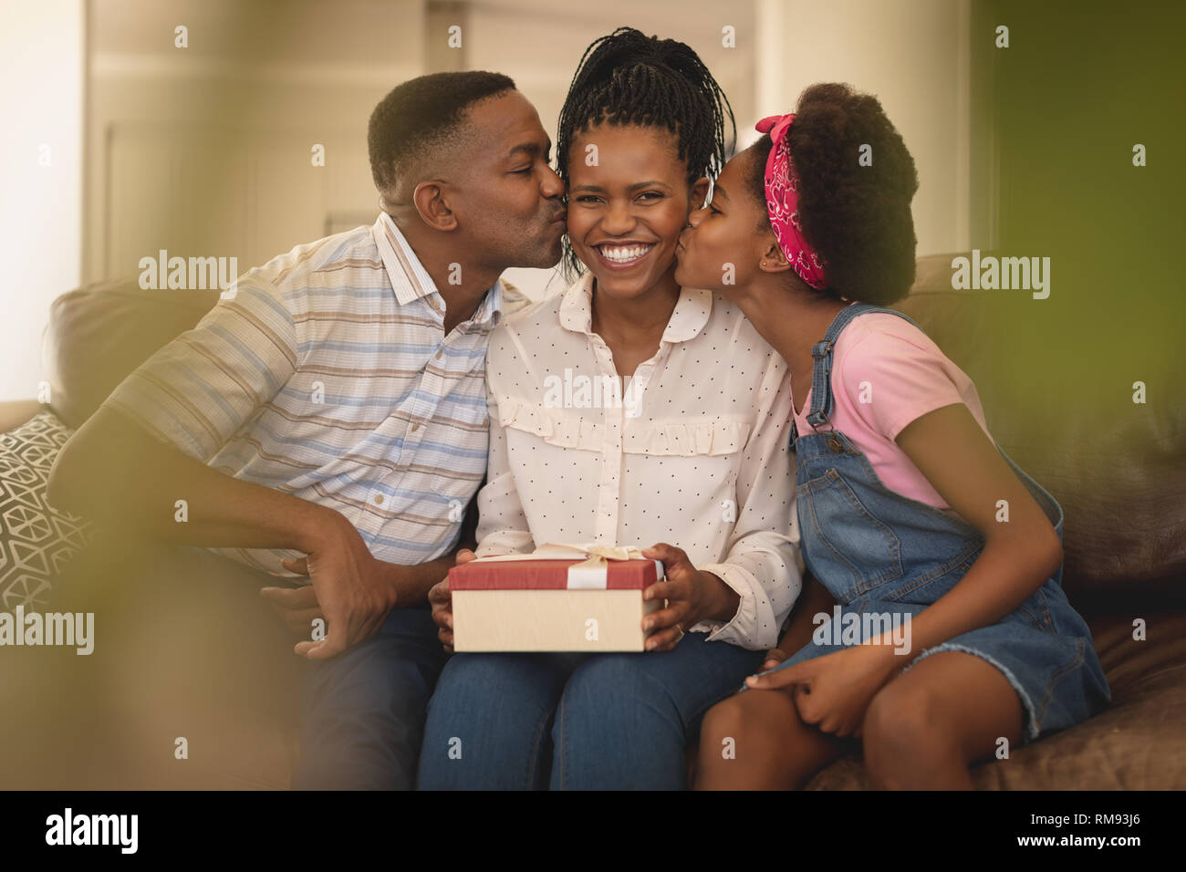Happy African American father and daughter kissing mother on cheeks Stock Photo