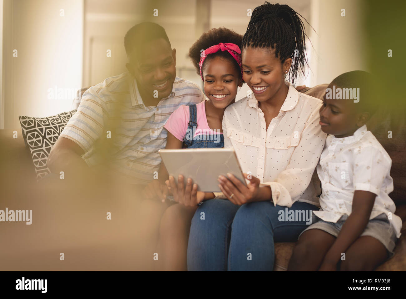Happy African American family sitting on the sofa and using digital ...