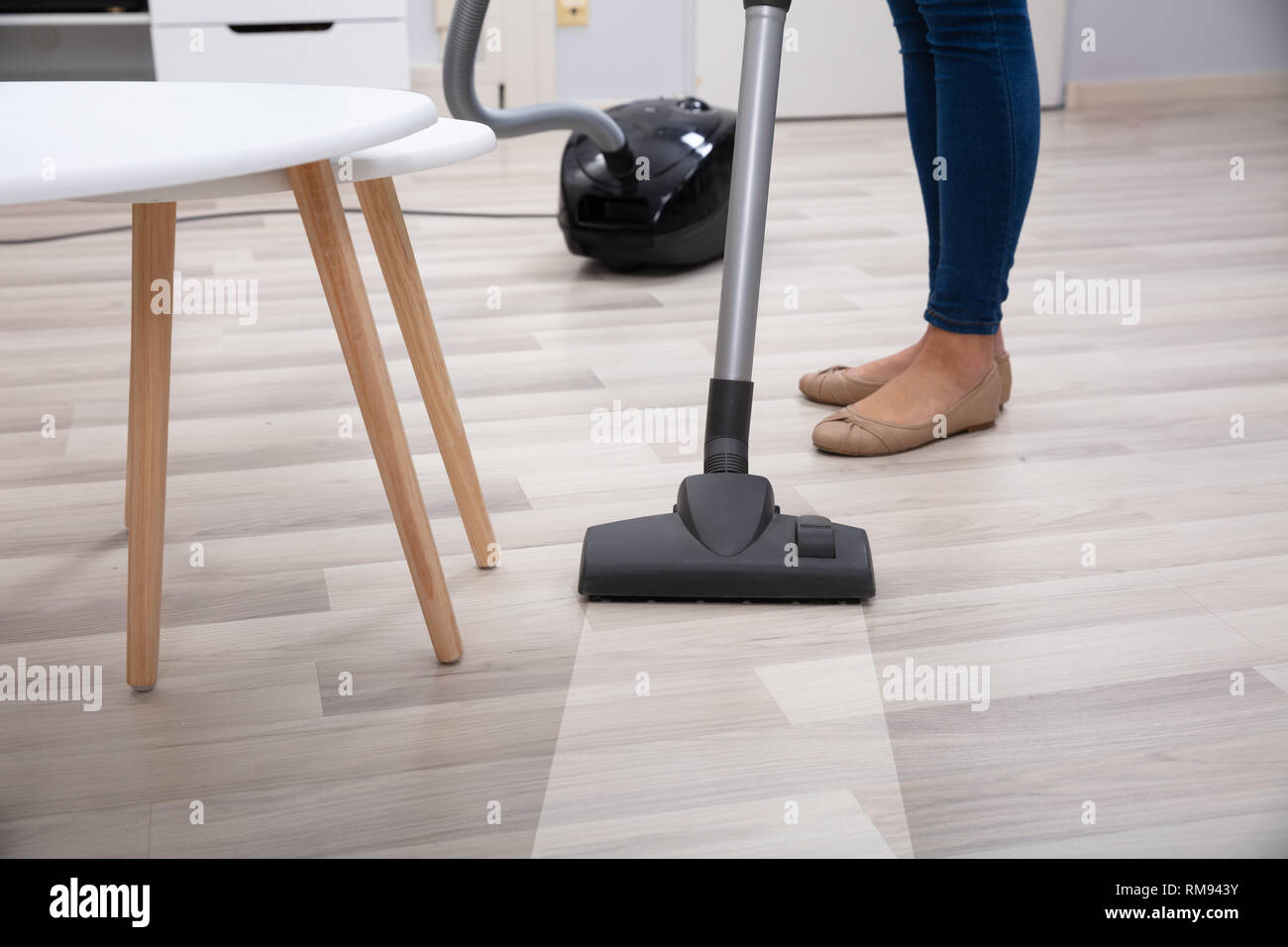 Low Section Of Person Using Vacuum Cleaner For Cleaning Hardwood