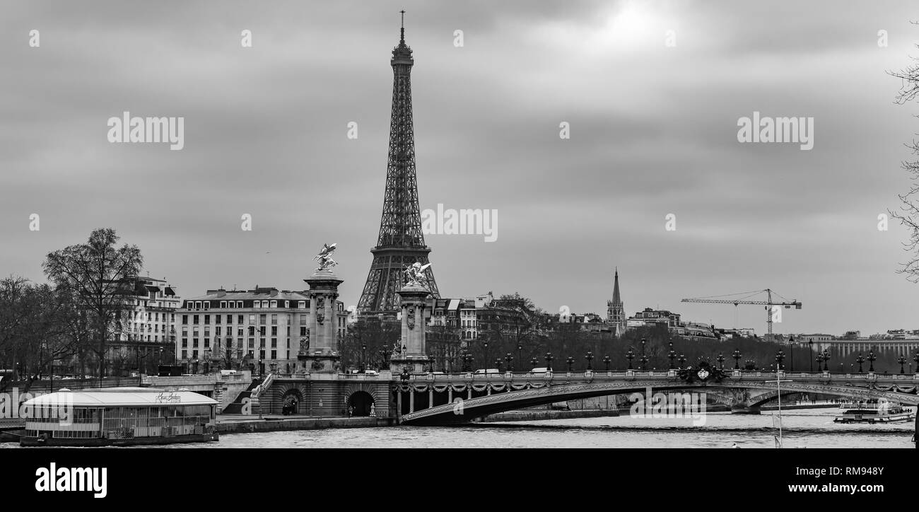Moody cityscape panorama with Pont Alexandre III bridge, Seine river and Eiffel Tower in Paris, France in black and white treatment Stock Photo