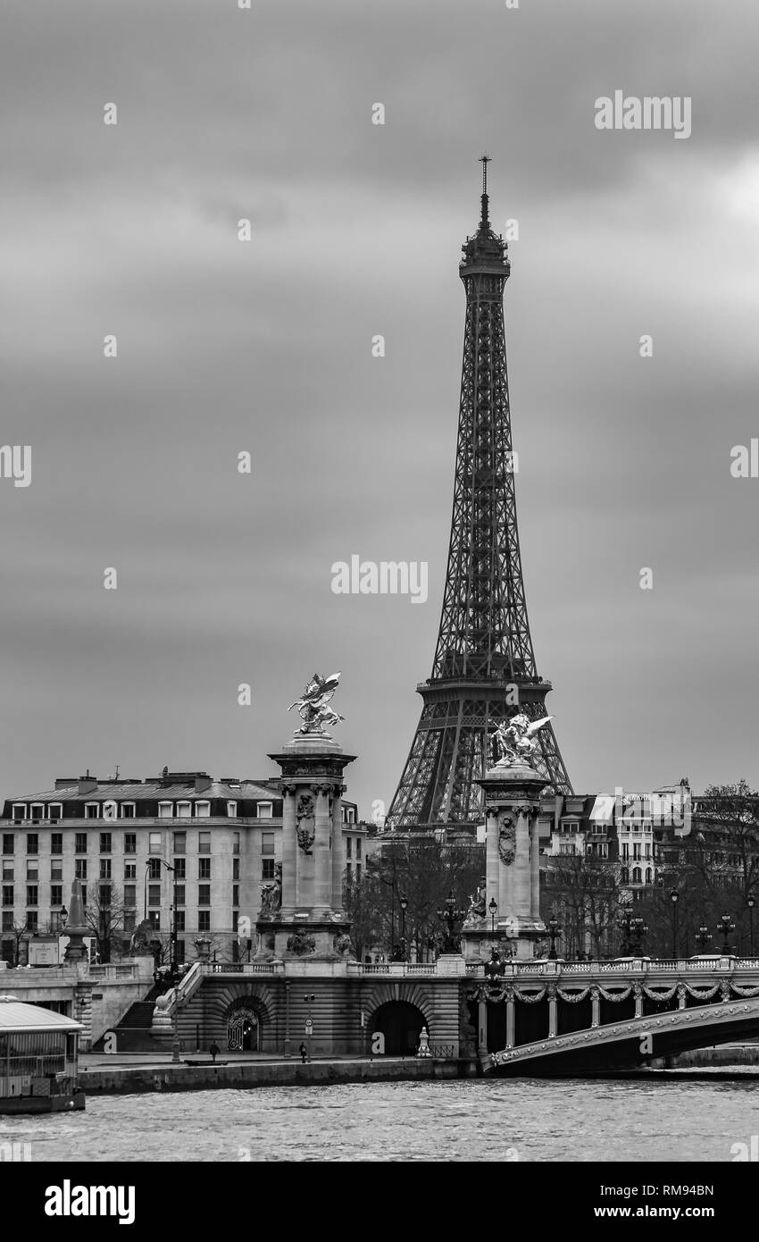 Moody cityscape with Pont Alexandre III bridge, Seine river and Eiffel Tower in Paris, France in black and white treatment Stock Photo