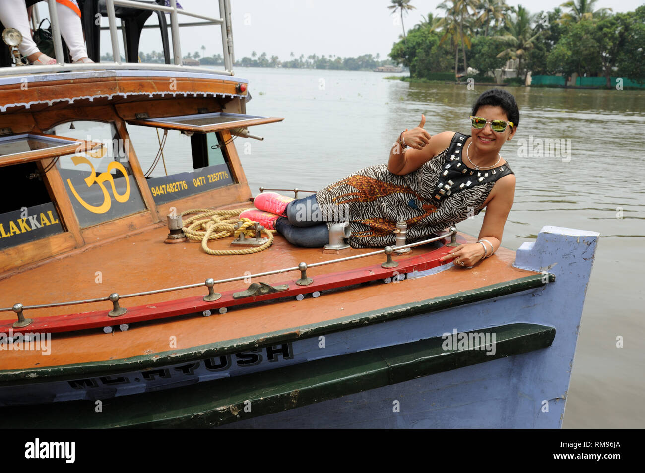 woman lying on deck of boat backwater, Munnar, Kerala, India, Asia, MR#802B Stock Photo