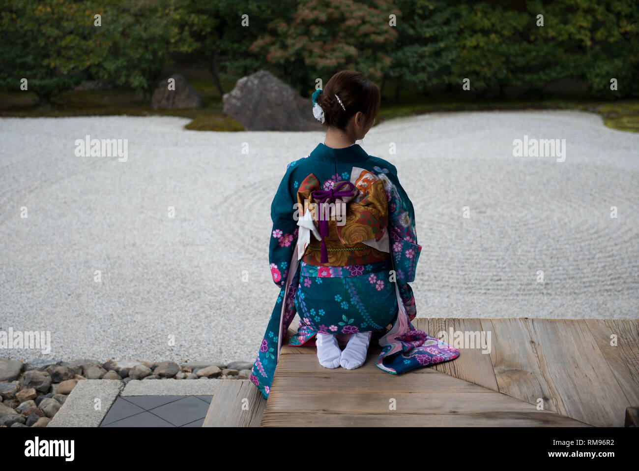 Geisha on Pavilion Verandah, Woman dressed in traditional kimonos outside pavillion kneeling by Japanese rock garden, Karesansui in Japanese, Kenni Stock Photo