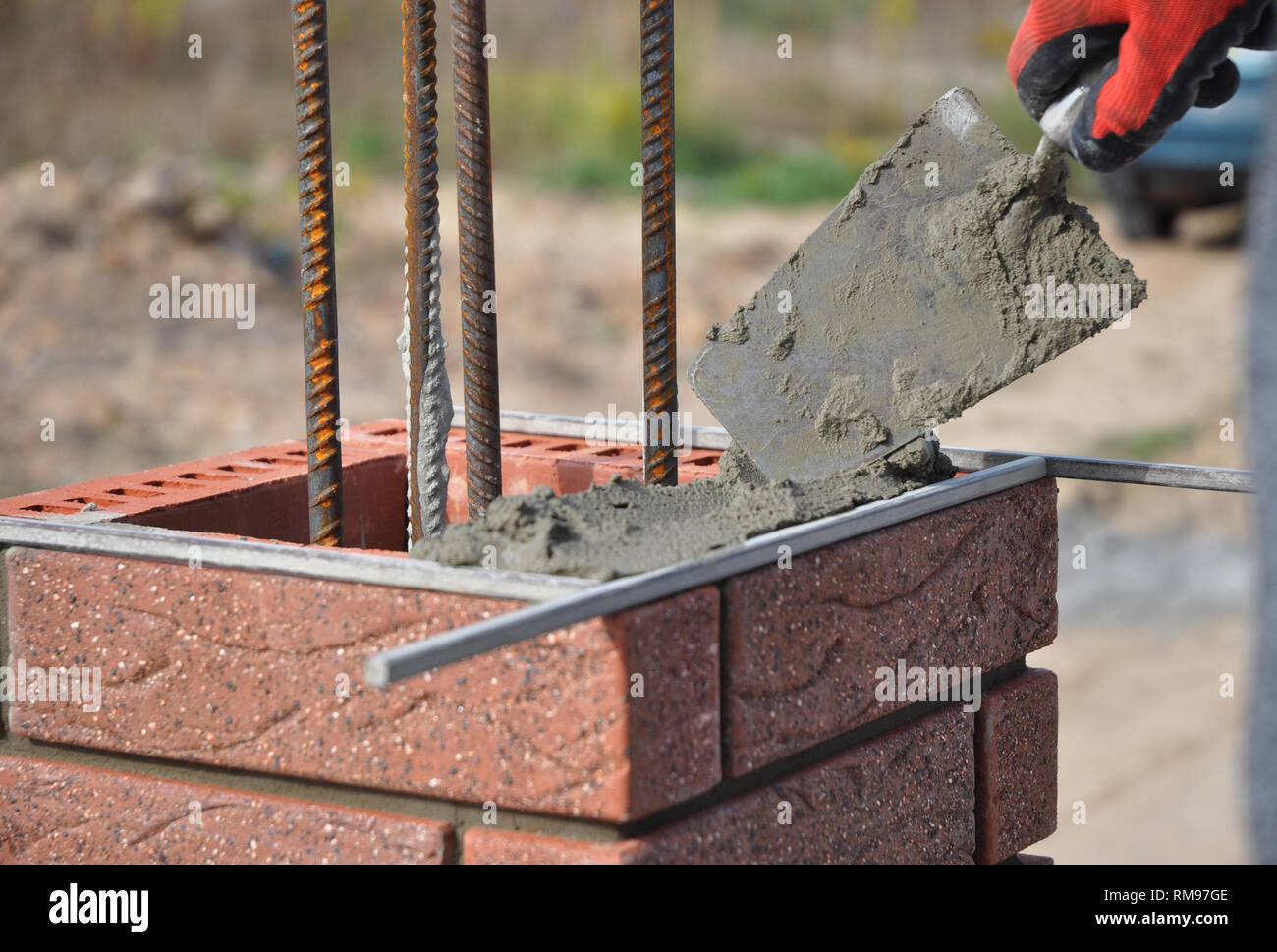 Bricklayer hand laying brick column with metal rod Stock Photo Alamy