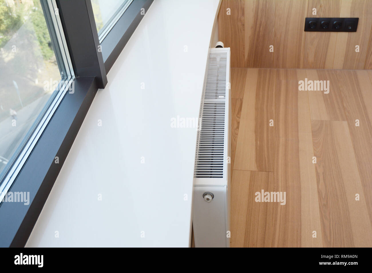 White radiator heating with thermostat and window sill. Stock Photo