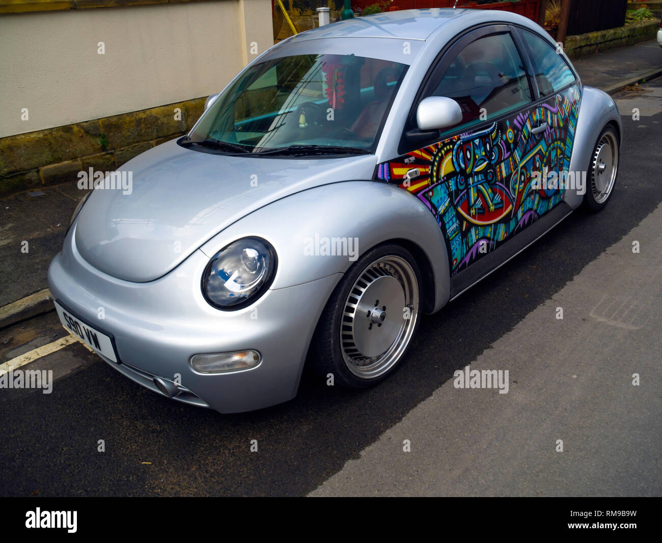 New type Volkswagen Beetle car in silver with artwork painted on the doors Stock Photo