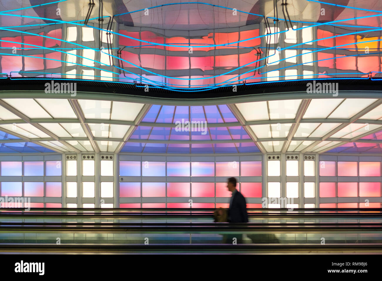 Air passenger, businessman, colourful neon lights art installation by Michael Hayden, pedestrian tunnel, Chicago O'Hare International Airport Terminal Stock Photo