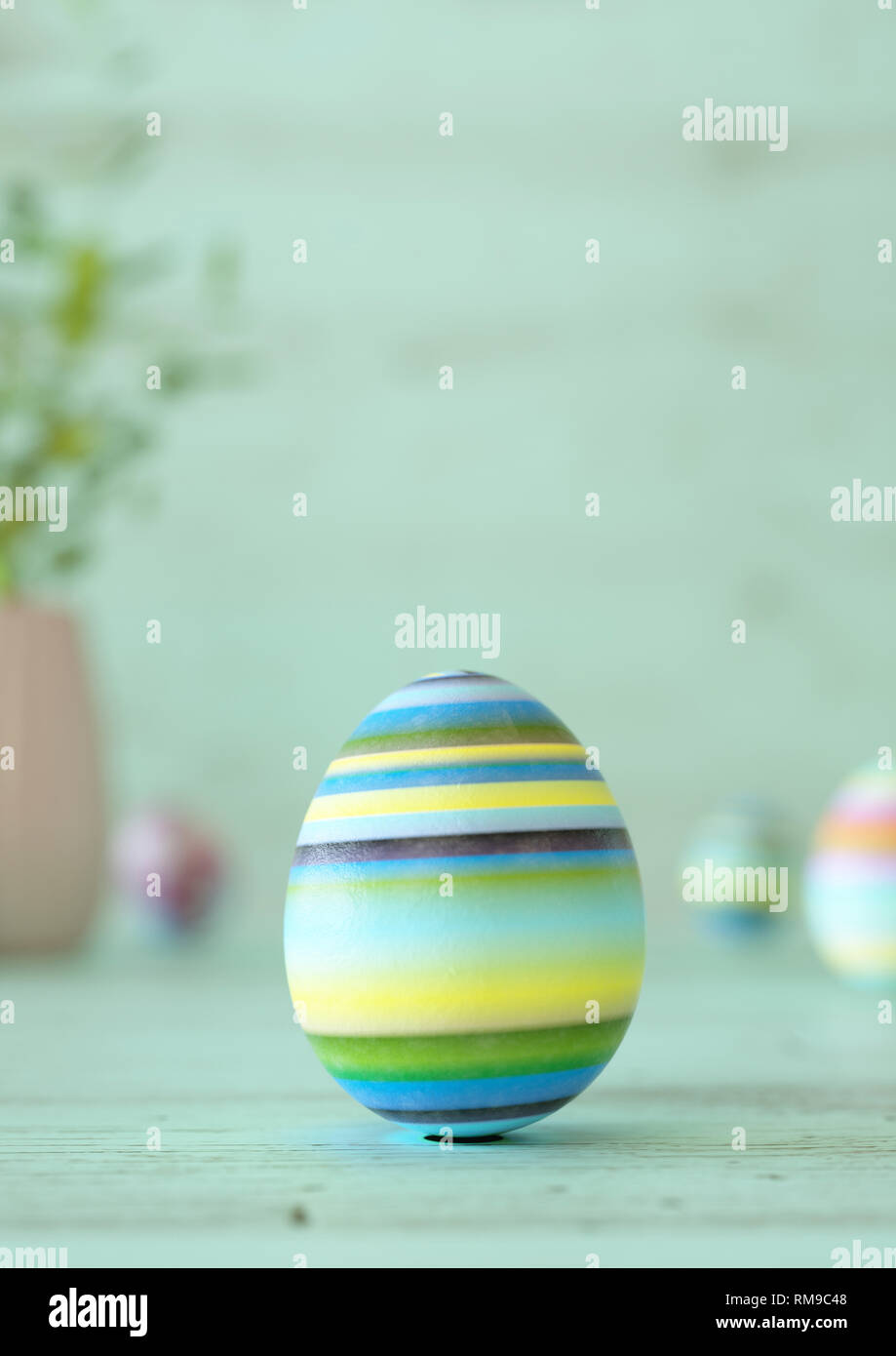 Easter egg standing on its blunt end, decorated in colorful stripes ...