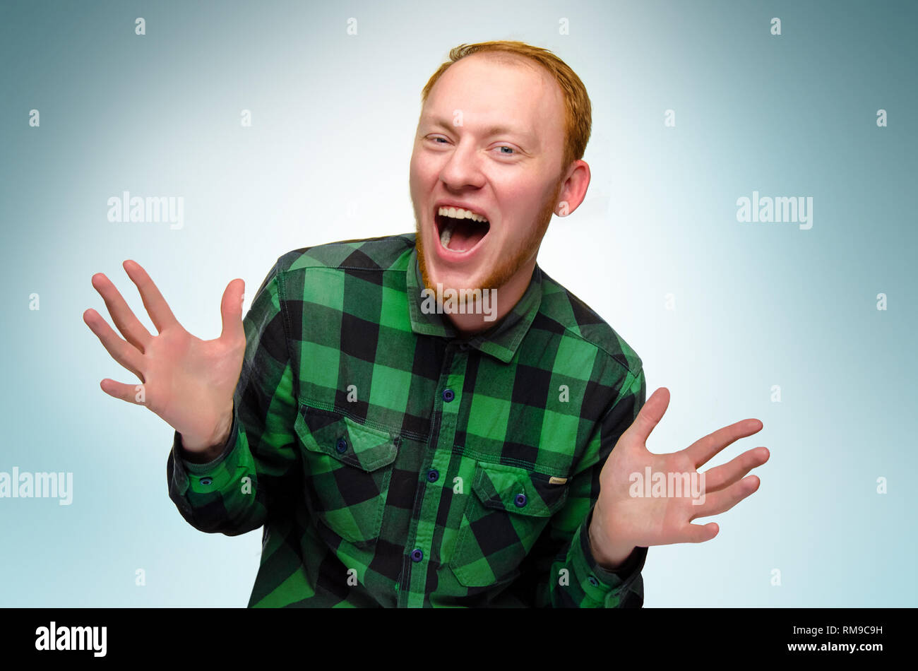 portrait of red haired happy man show his hands. caucasian teenager maked surprise. redhead guy scream and laughs. reaction to surprise is overjoyed shock. emotion is glad. confident, funny boy smile Stock Photo