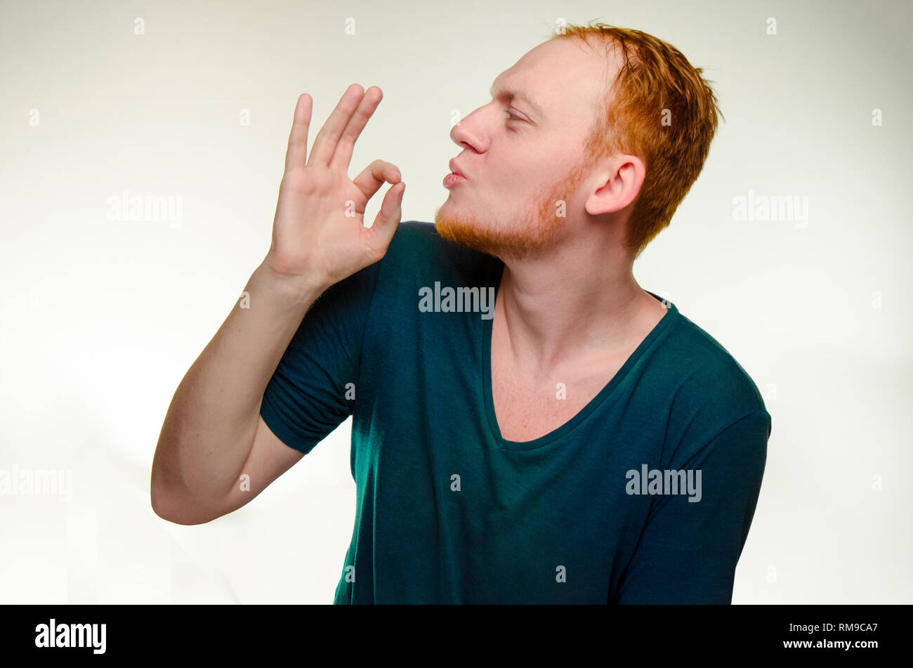 playful, cheerful, red haired man show gesture perfecto. caucasian male gourmet like tasty delicious. great job. positivity emotion. symbol is fingers, hand near lips, mouth Stock Photo