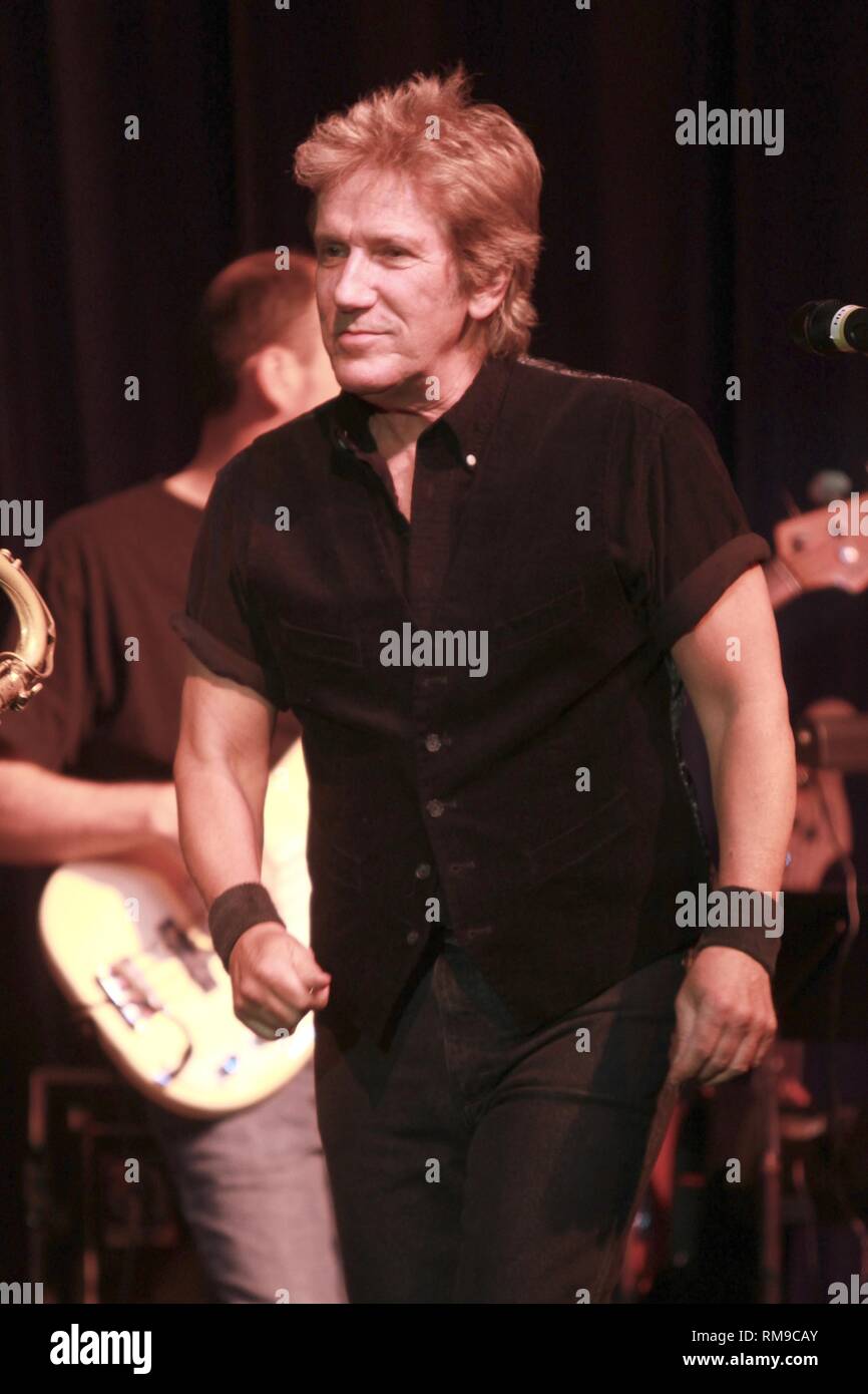 Musician John Cafferty is shown performing on stage during a "live