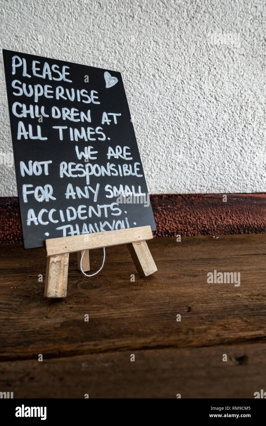 mini easel with a hand written 'Please supervise Children' sign on a blackboard in an English cafe Stock Photo