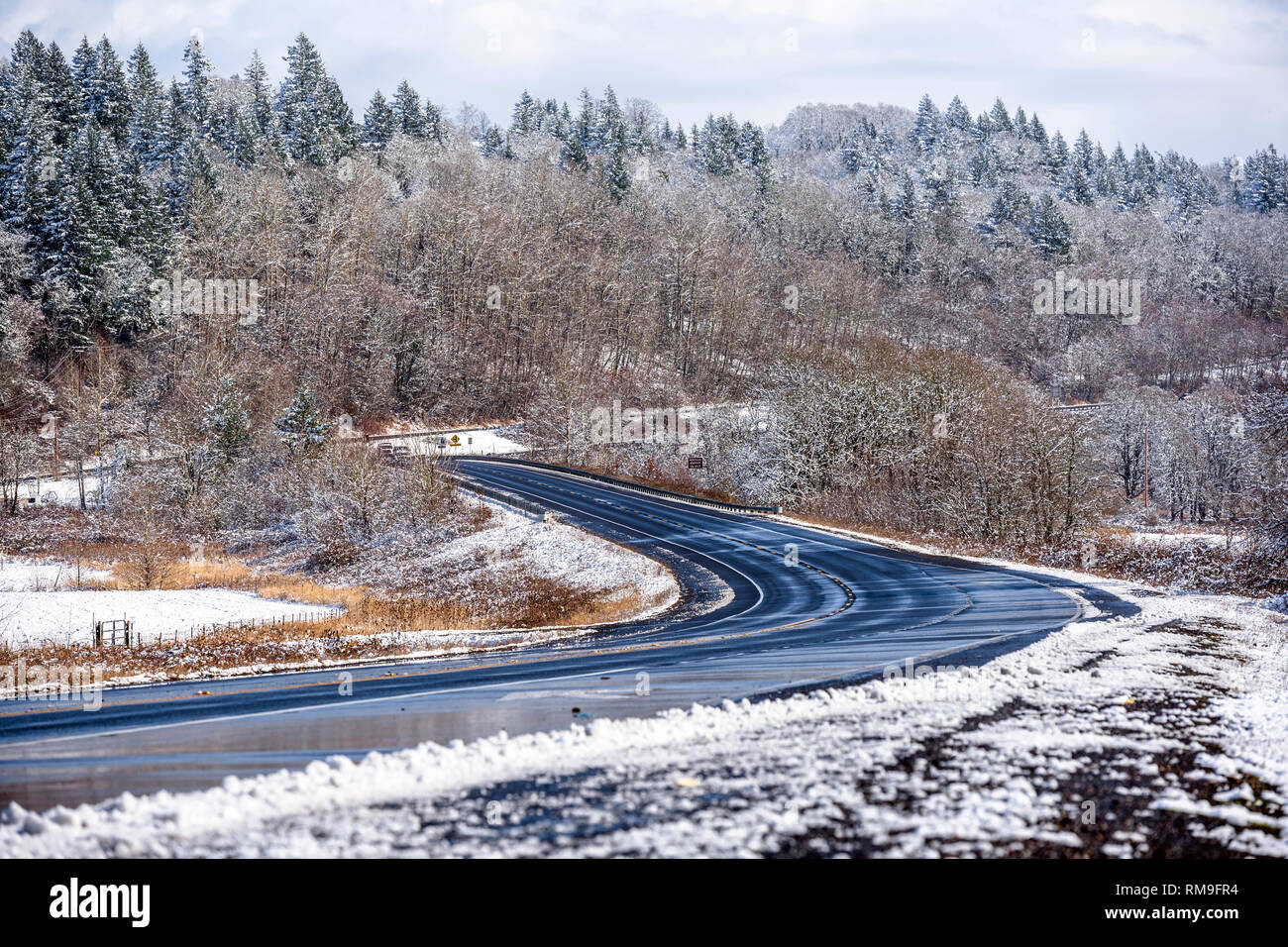 Winter landscape with winding road and hills with snow-covered trees ...