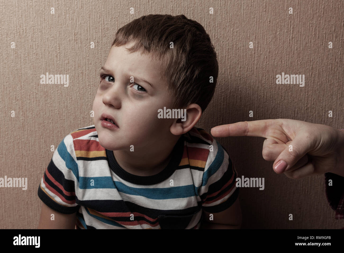 Family violence. Child abuse. Sad child with bruises under his eyes and an adult rugaent Stock Photo