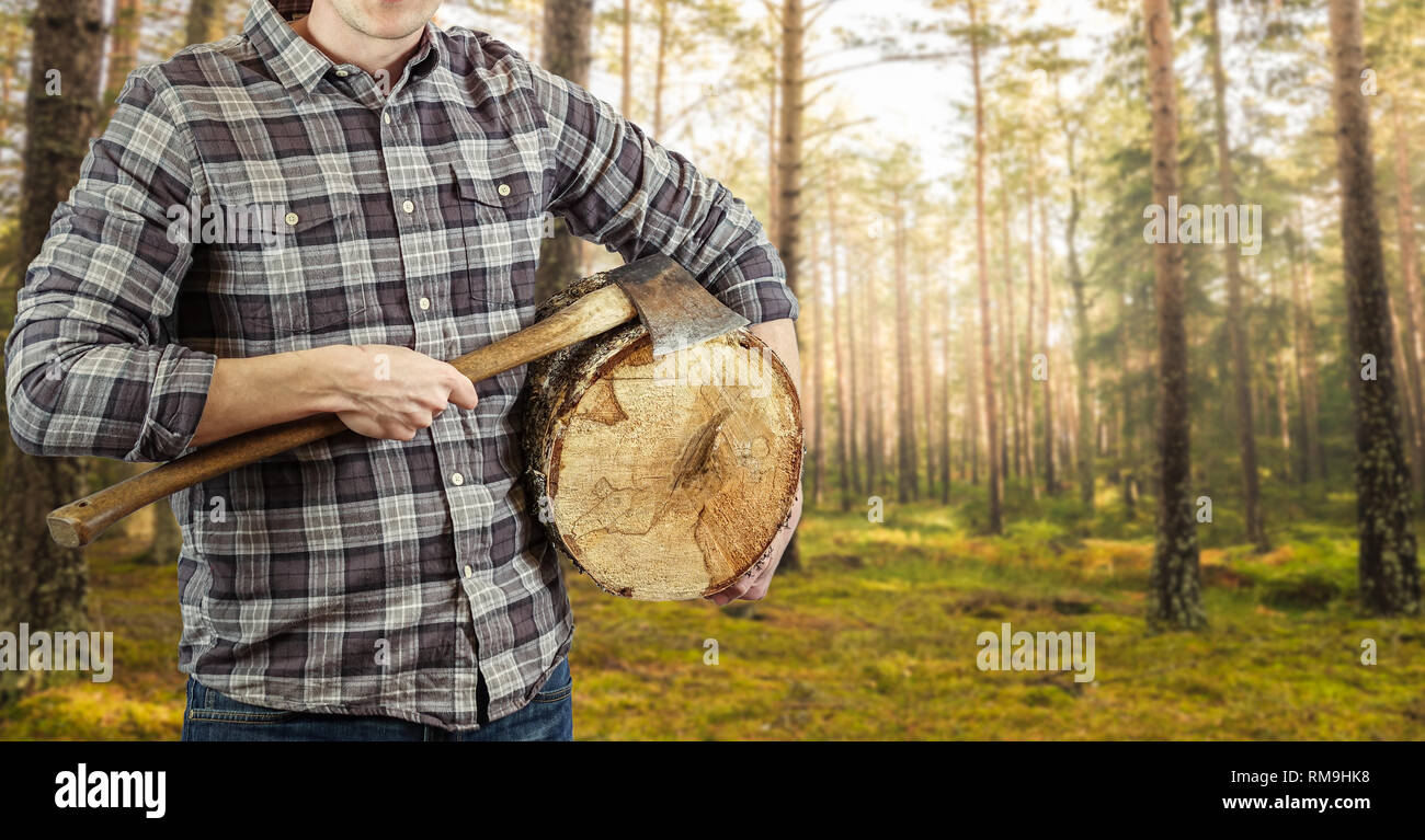A lumberjack with an ax in his hand and a log. Logger with checkered shirt. Plenty of copy space for your own text or product. Stock Photo