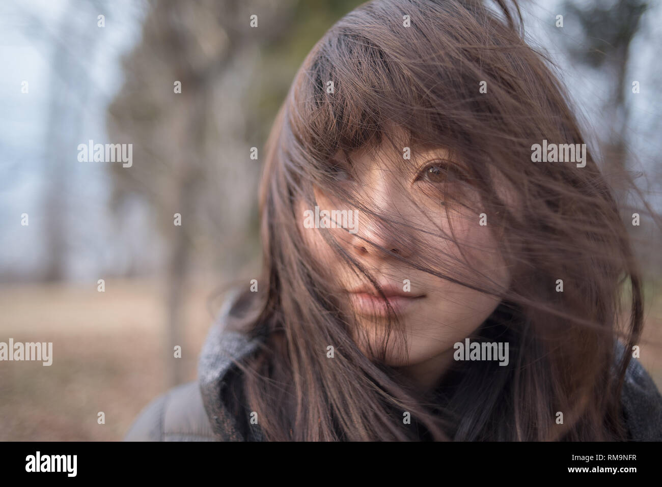 Outside scene in nature with beautiful and cute young woman and her brown hair in the wind contemplating the scenery. Japan. Stock Photo