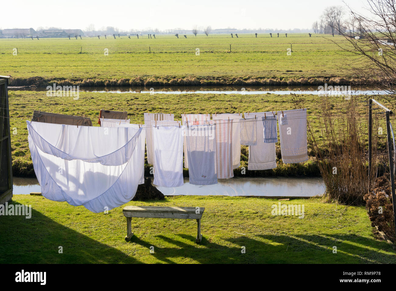 Clean clothes drying in the wind on a washing line on a beautiful sunny day in spring. Situated in a beautiful typical Dutch flat landscape with grass Stock Photo