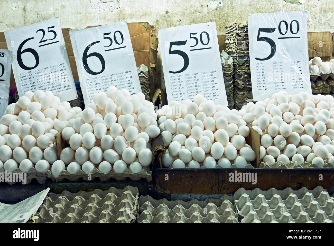 Piles of heaped white eggs and trays with corresponding price signs at