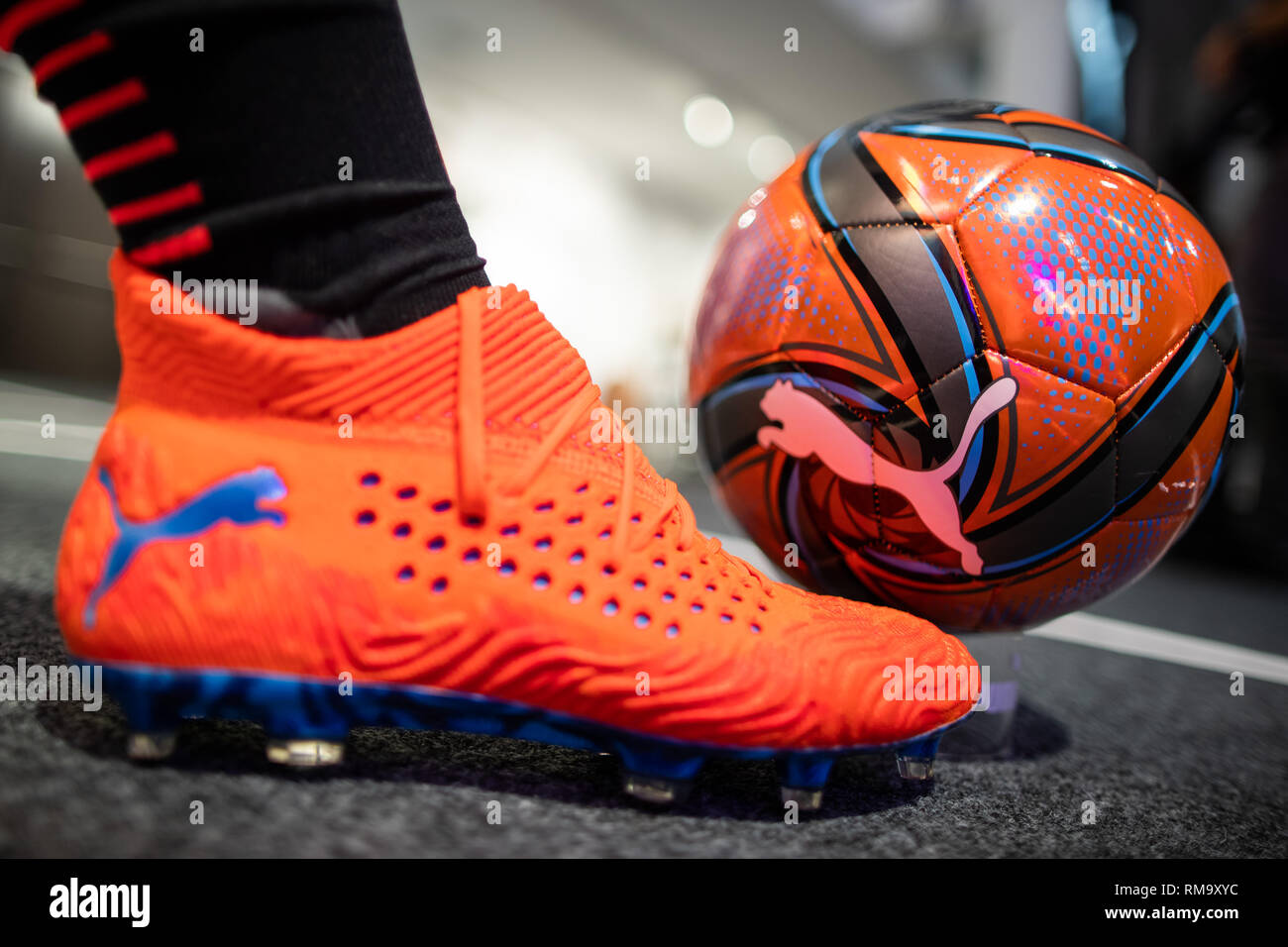 14 February 2019, Bavaria, Herzogenaurach: A football and a football shoe  with the logo of the sporting goods manufacturer Puma SE stand are  exhibited in the company. On 14 February, the sporting