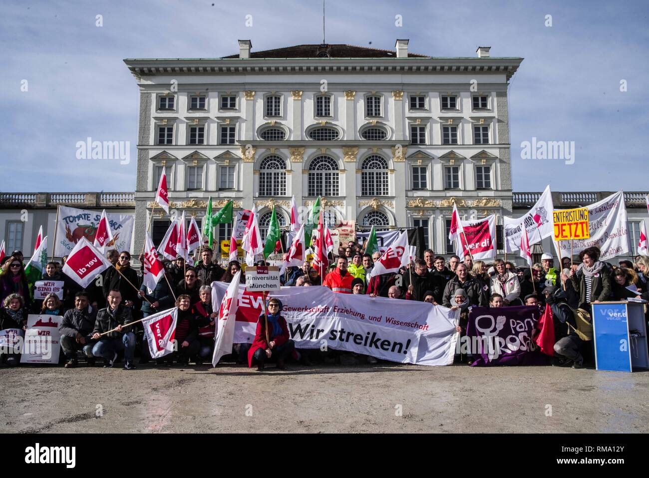 Munich, Bavaria, Germany. 14th Feb, 2019. Striking Verdi union employees pose in front of the famed Schloss Nymphenburg castle in Munich. To signify the failure of the second round of talks with employers, the German Verdi Ver.di labor union organized a 200  strong flashmob action at the famed Schloss Nymphenburg in Munich to kick off a new strike wave. Credit: ZUMA Press, Inc./Alamy Live News Stock Photo