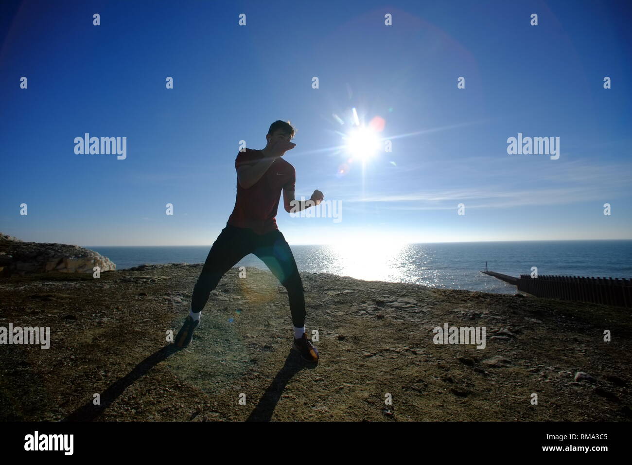 Seaford, East Sussex, UK. 14th Feb, 2019. People enjoying the bright warm sunshine on Seaford Beach, pictured is Sonny Parkinson shadow boxing on the chalk cliffs above Seaford. Credit: Peter Cripps/Alamy Live News Stock Photo