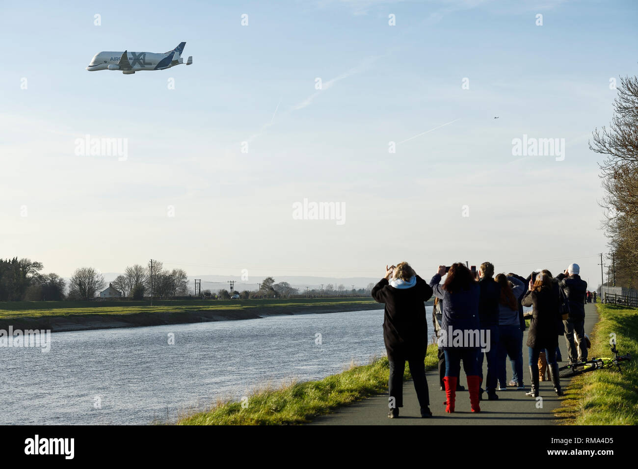Broughton, Flintshire, UK. 14th February 2019. Crowds watch the new Airbus A330-743L transport plane known as the Airbus Beluga XL do a fly past at Hawarden Airport. The airport is adjacent to the Airbus factory on the outskirts of Chester and this is the first visit of the plane to the factory where it will remain until Saturday. The Beluga XL is designed to transport aircraft wings and has 30% more cargo capacity than the current Beluga. Credit: Andrew Paterson/Alamy Live News Stock Photo