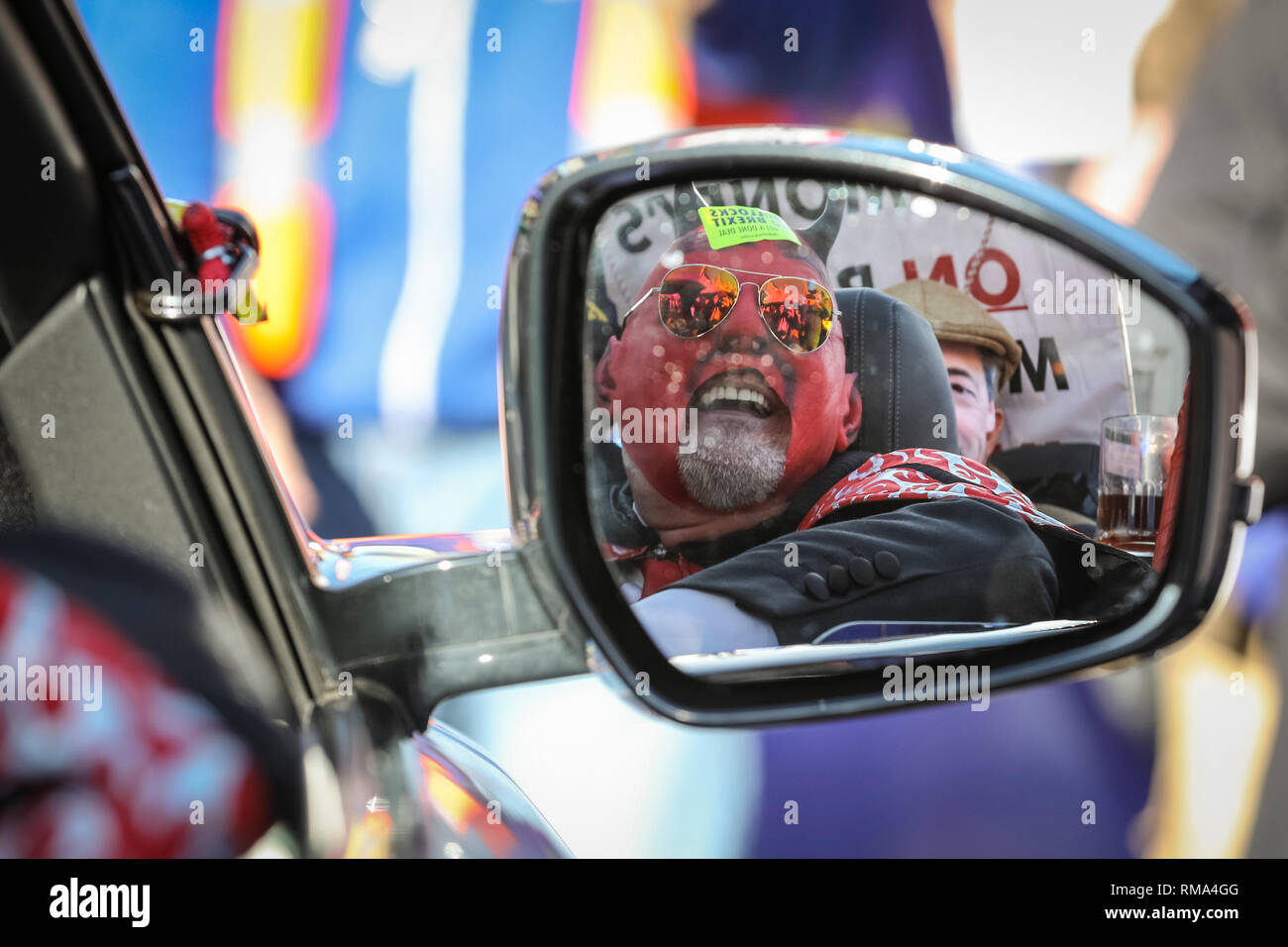 Westminster, London, UK. 14th Feb, 2019. The Devil is reflected in a car mirror. Remainers have organised a 'Fake Politicians' car, including Faux Bojo, Facob Rees-Mogg, a Fake Farage, a puppet of Theresa May, and a 'Devil'. Pro- and anti-Brexit protesters rally, wave flags and hold placards outside the Houses of Parliament and near the College Green media platforms in Westminster. Many have turned up in costumes and colourful outfits to get their message across. Credit: Imageplotter News and Sports/Alamy Live News Stock Photo