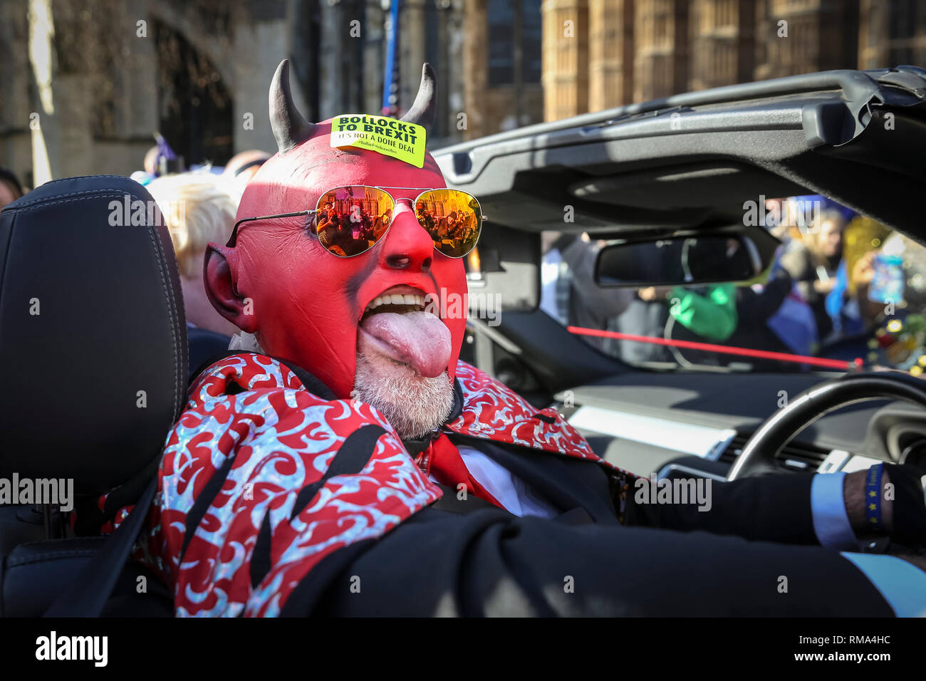 Westminster, London, UK. 14th Feb, 2019. The devil is on board and is in a fun mood. Remainers have organised a 'Fake Politicians' car, including Faux Bojo, Facob Rees-Mogg, a Fake Farage, a puppet of Theresa May, and a 'Devil'. They are joined by 'EU Supergirl' Madeleina Kay (left) Pro- and anti-Brexit protesters rally, wave flags and hold placards outside the Houses of Parliament and near the College Green media platforms in Westminster. Many have turned up in costumes and colourful outfits to get their message across. Credit: Imageplotter News and Sports/Alamy Live News Stock Photo