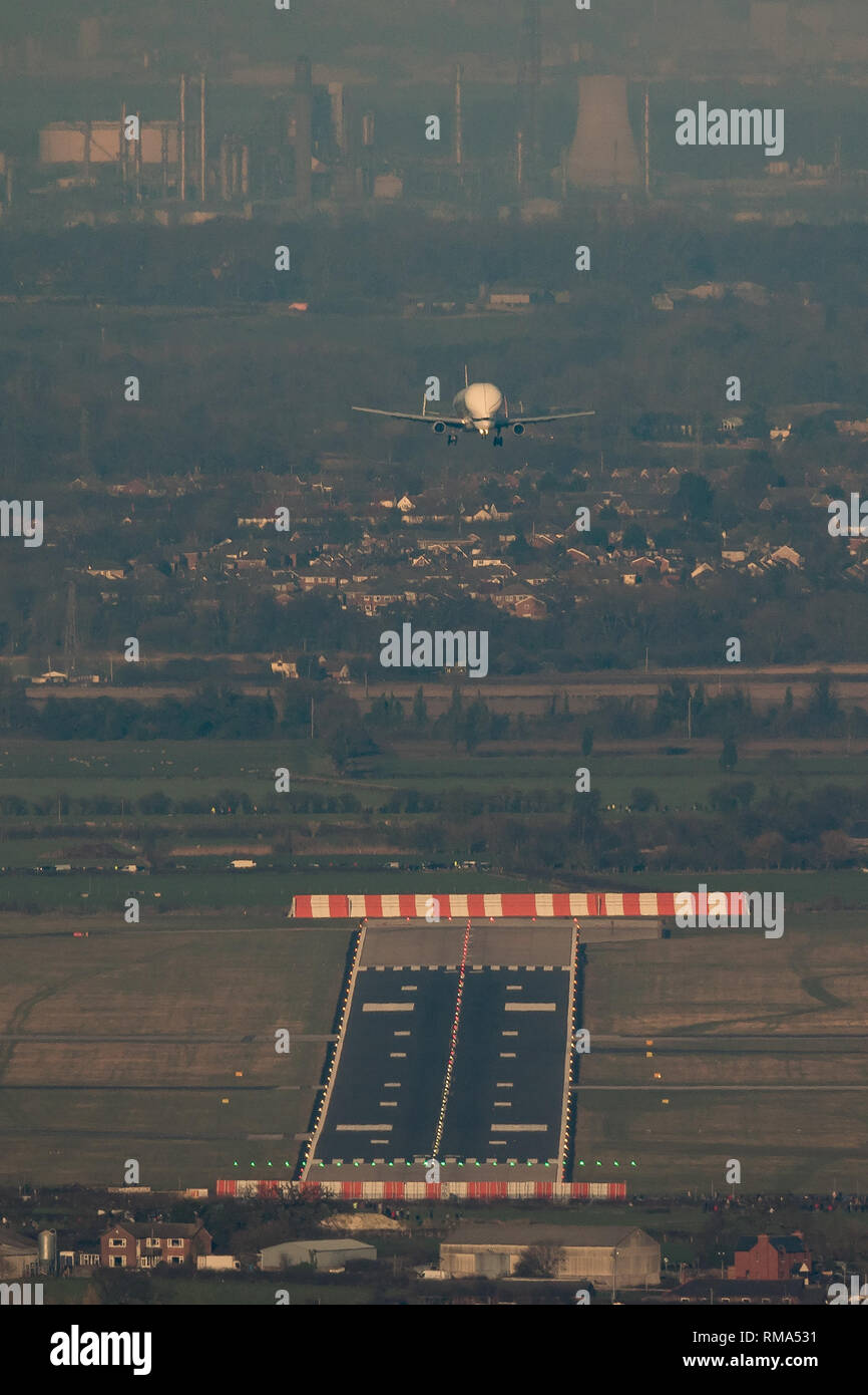 Hawarden Aerodrome/Broughton, UK. 14h February, 2019. Viewed from Waun-Y-Llyn country park, Hope Mountain, Wales, the Airbus BelugaXL lands in the UK for the first time as it visits Airbus Broughton as part of its test programme. The elevated location provides a different viewpoint with Ellesmere Port providing the backdrop and the many spectators vehicles visible on the surrounding roads Designed, built and to be operated by Airbus this successor to the Beluga will be used to move oversized aircraft components between Airbus sites. Credit: Paul Bunch / Alamy Live News. Stock Photo