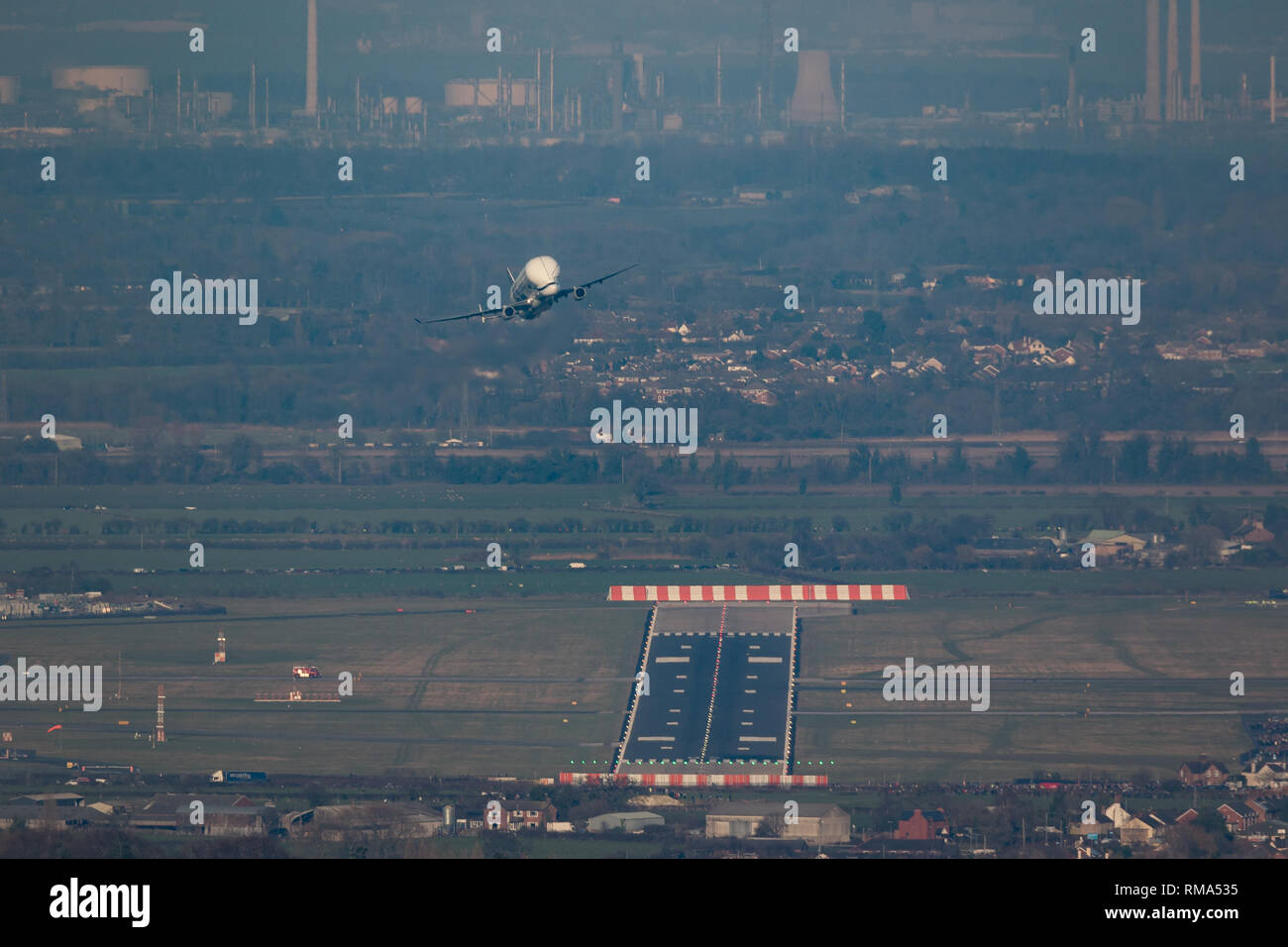 Hawarden Aerodrome/Broughton, UK. 14h February, 2019. Viewed from Waun-Y-Llyn country park, Hope Mountain, Wales, the Airbus BelugaXL lands in the UK for the first time as it visits Airbus Broughton as part of its test programme. The elevated location provides a different viewpoint with Ellesmere Port providing the backdrop and the many spectators vehicles visible on the surrounding roads Designed, built and to be operated by Airbus this successor to the Beluga will be used to move oversized aircraft components between Airbus sites. Credit: Paul Bunch / Alamy Live News. Stock Photo