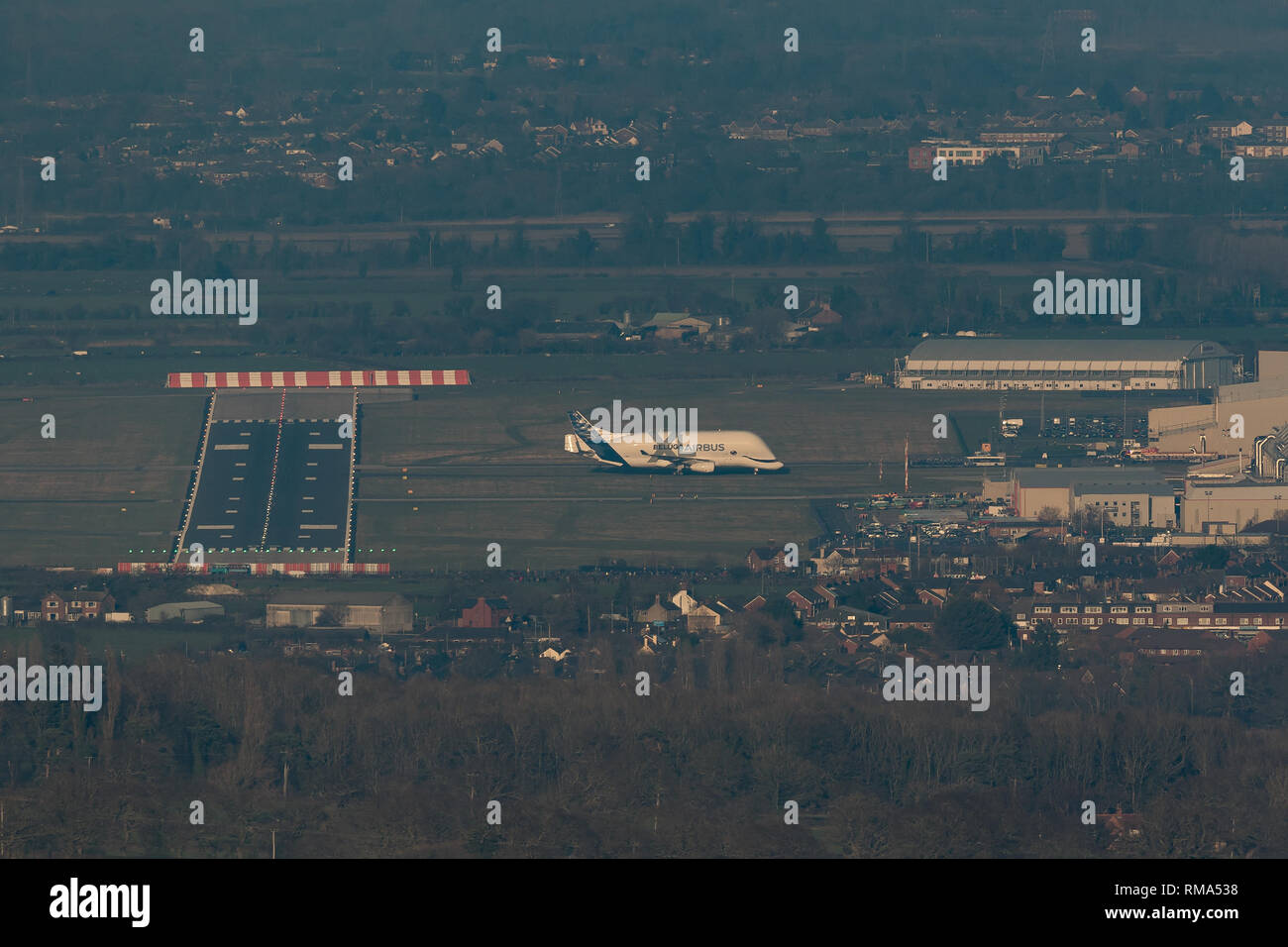 Hawarden Aerodrome/Broughton, UK. 14h February, 2019. Viewed from Waun-Y-Llyn country park, Hope Mountain, Wales, the Airbus BelugaXL lands in the UK for the first time as it visits Airbus Broughton as part of its test programme. The elevated location provides a different viewpoint with Ellesmere Port providing the backdrop and the many spectators vehicles visible on the surrounding roads Designed, built and to be operated by Airbus this successor to the Beluga will be used to move oversized aircraft components between Airbus sites. Credit: Paul Bunch / Alamy Live News. Stock Photo