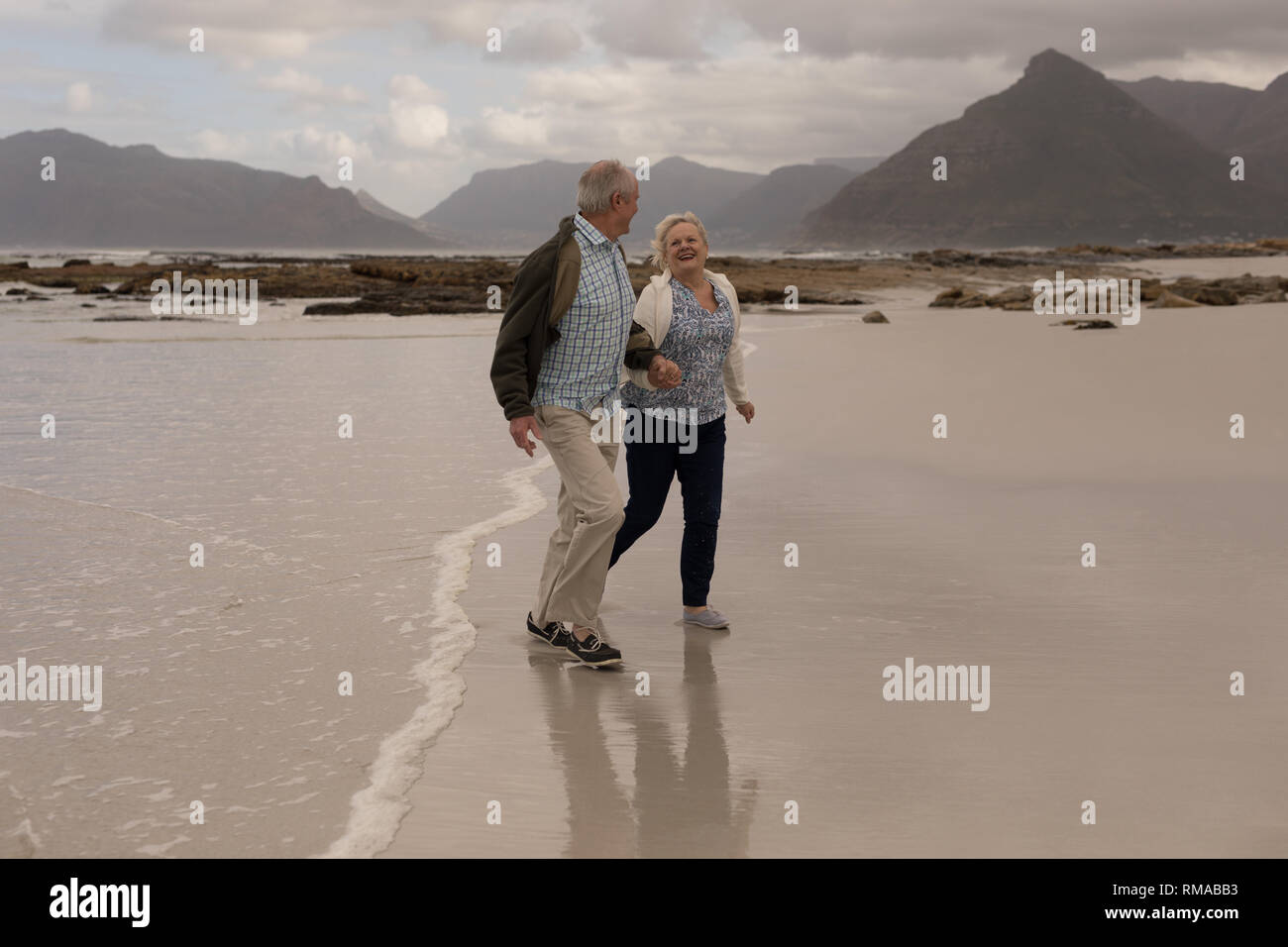 Senior couple walking hand in hand at the beach Stock Photo - Alamy
