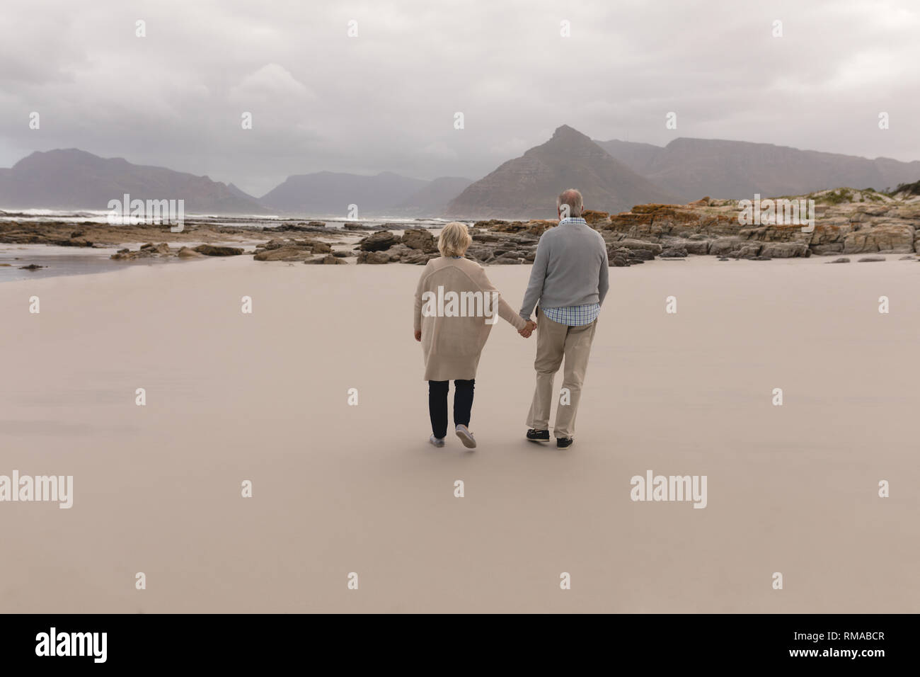 Happy senior couple walking hand in hand at the beach Stock Photo - Alamy