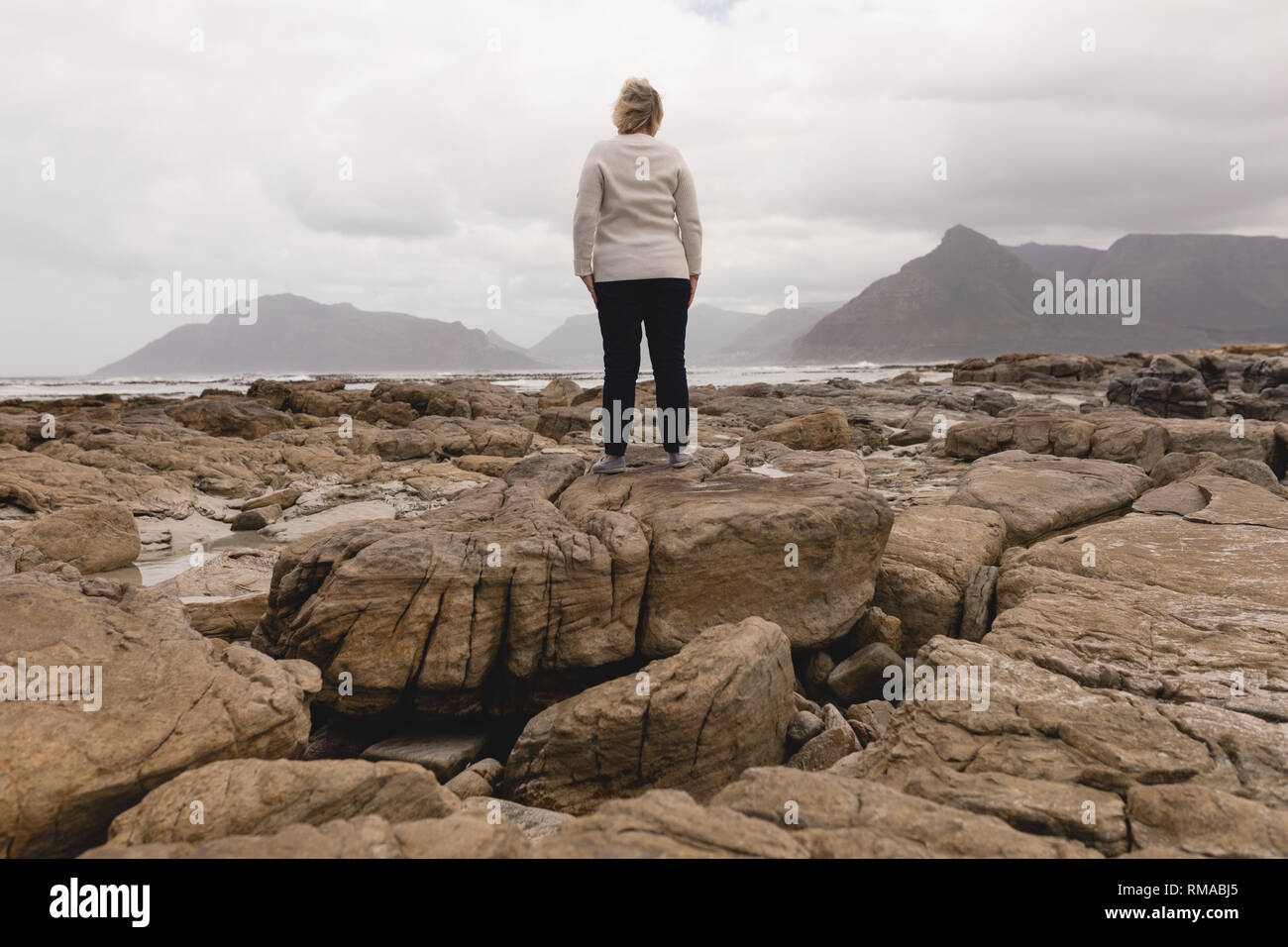 Happy senior woman standing on the rock at beach Stock Photo