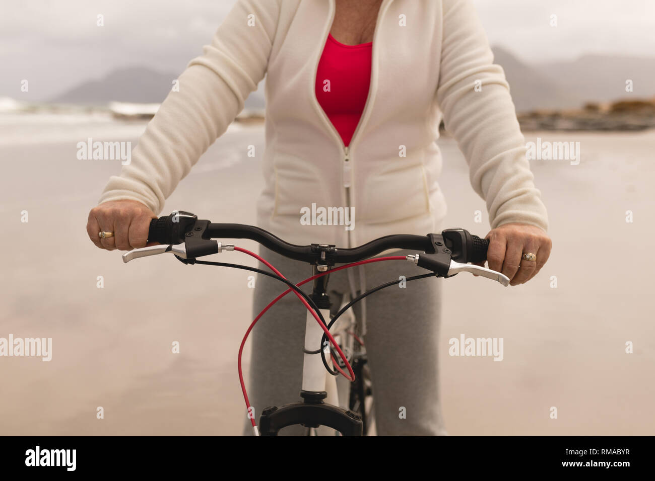 Senior woman riding a bicycle on the beach Stock Photo