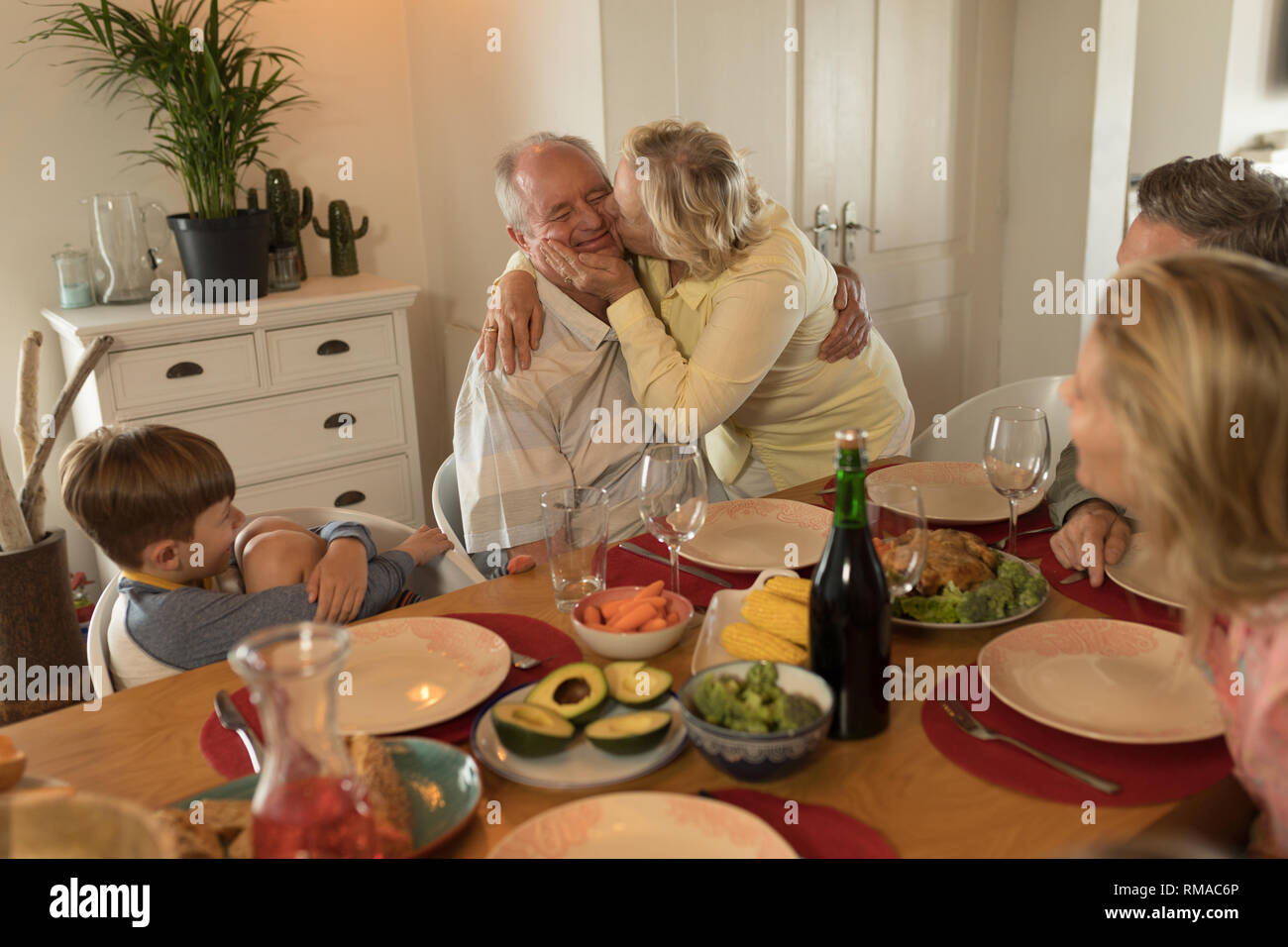 Family interacting with each other while having meal on dining table Stock Photo
