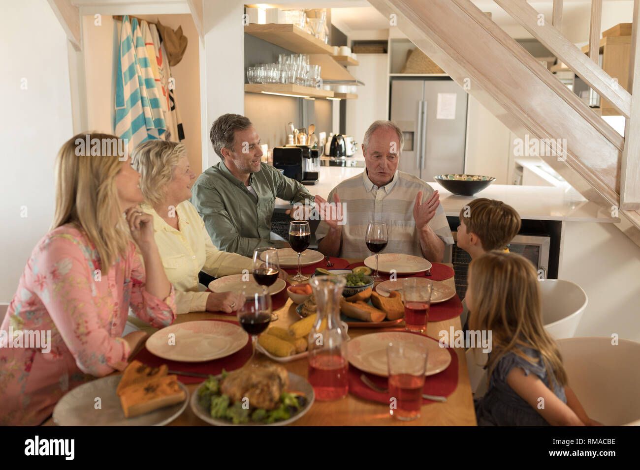 Family interacting with each other while having meal on dining table Stock Photo