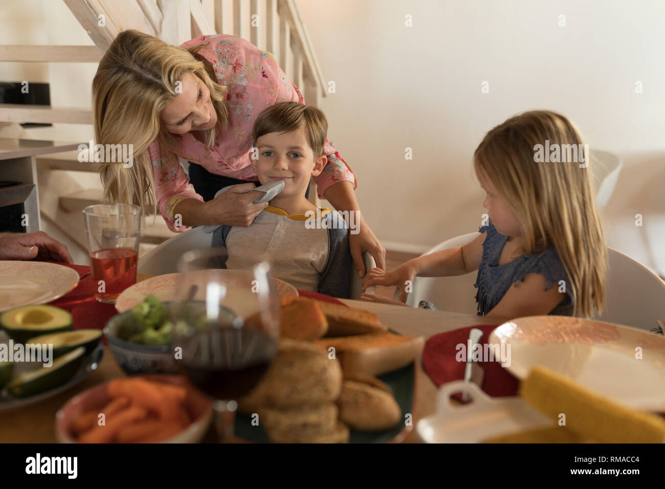 Mother wiping her sons mouth with napkin on dining table Stock Photo