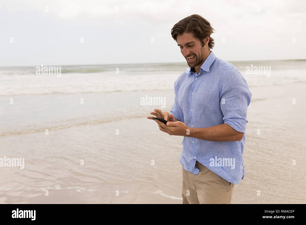 Man using mobile phone on the beach Stock Photo