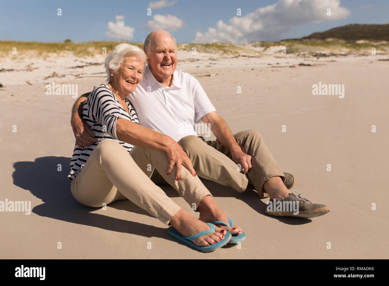 Happy senior couple sitting on beach Stock Photo