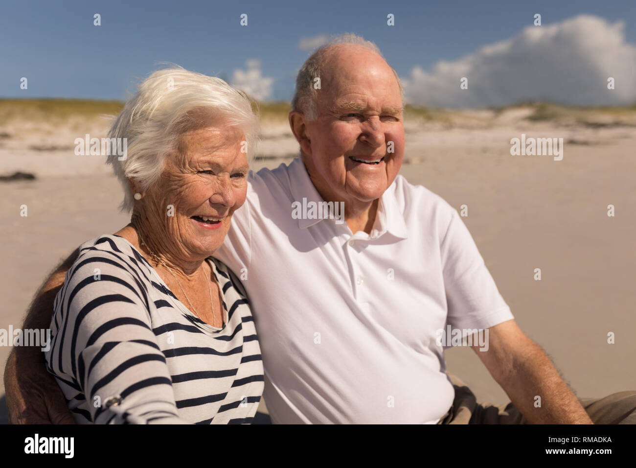 Happy senior couple sitting on beach Stock Photo