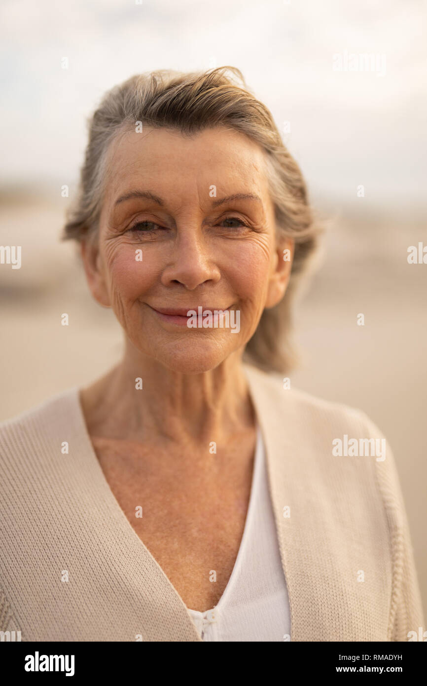 Happy senior woman standing on the beach Stock Photo