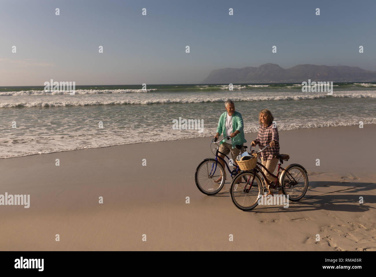 Senior couple walking with bicycle on the beach Stock Photo